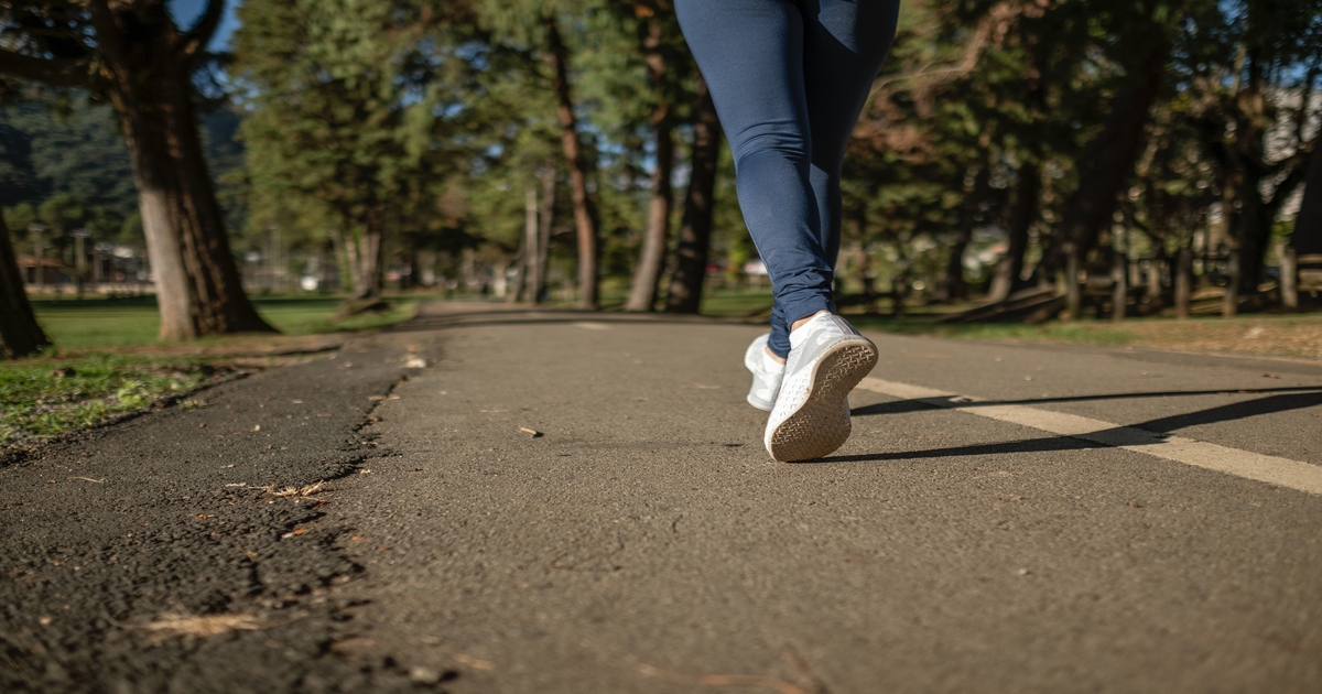 A close-up of a person's legs walking on a park pathway, showcasing the active lifestyle promoted by walking reward apps.