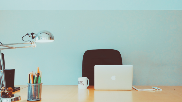 A minimalist home office setup, ideal for someone starting 'Online Jobs for Beginners.' The image features a sleek laptop, a mug, a collection of pencils, and a lamp on a wooden desk, representing a serene workspace where a beginner can embark on the journey to earning a potential $5000 monthly online.