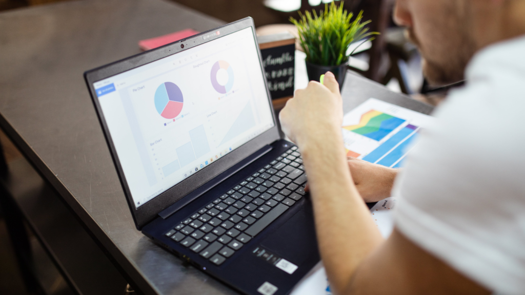 A person analyzing data charts on a laptop screen, with a focus on pie and bar charts, indicating a review of analytics.