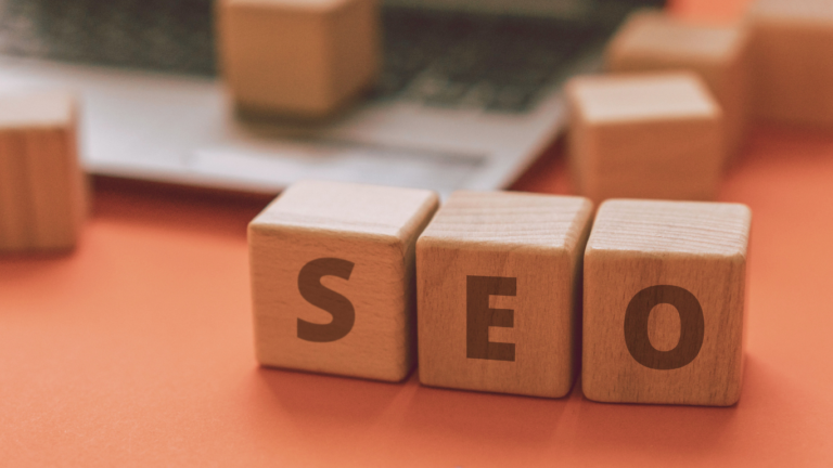 Wooden blocks spelling out 'SEO' on an orange background, symbolizing the fundamentals of SEO Basics.