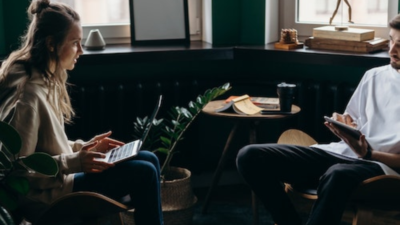 Two individuals engaged in translating literature on digital devices, sitting opposite each other in a cozy, book-adorned cafe. This scene represents the enriching process of translating beloved stories to make them accessible to a wider audience, showcasing how 'Make Money Reading Books' can also mean connecting cultures through the art of translation.