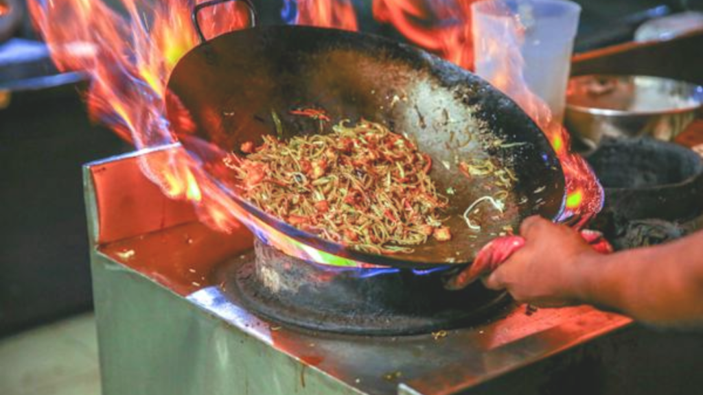 Intense flames envelop a wok, where a stir-fry cooks rapidly, symbolizing the swift and fiery speed desired for website performance.