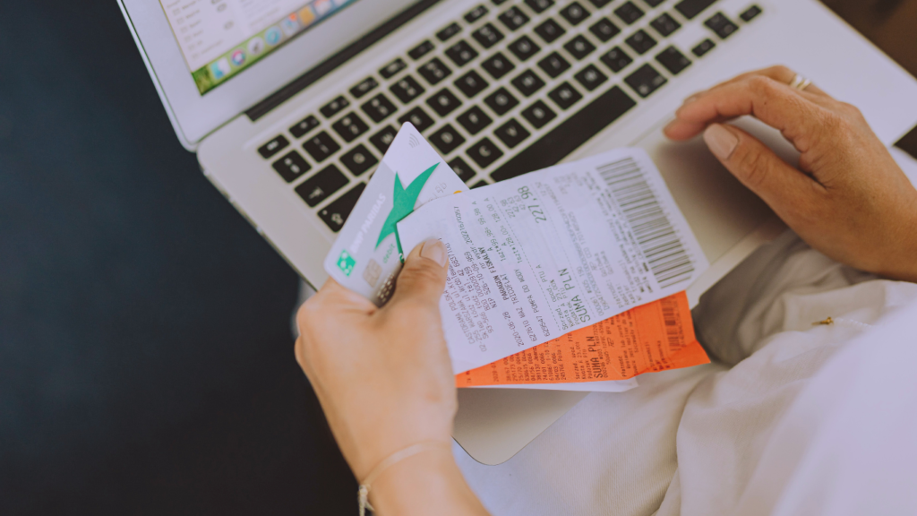 A person holding a credit card and a shopping receipt next to a laptop, depicting the use of Holiday Shopping Savings Apps that reward you for purchases.