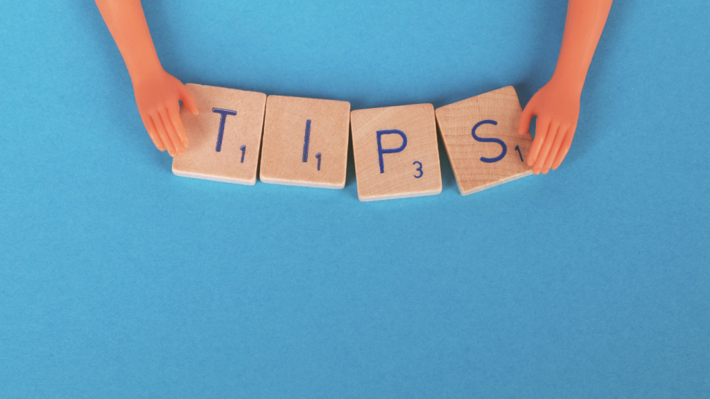 Toy hands arranging Scrabble letters spelling 'TIPS' on a bright blue background, symbolizing advice for maximizing rewards and savings with Holiday Shopping Savings Apps.