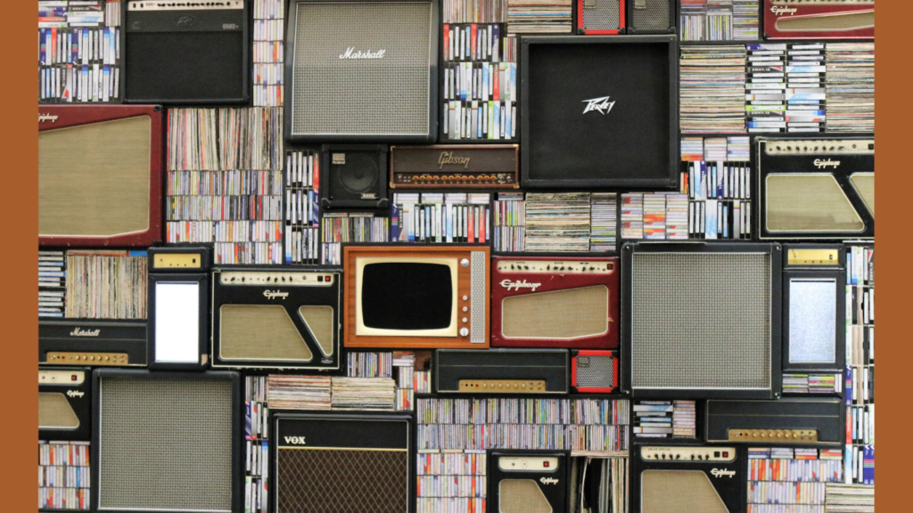 A wall creatively adorned with an array of guitar amplifiers from brands like Marshall, Gibson, and VOX, interspersed with shelves filled with an extensive collection of CDs. This image represents how music enthusiasts can listen to music and get paid online through platforms like SliceThePie by reviewing songs and amplifying their voices in the music community.